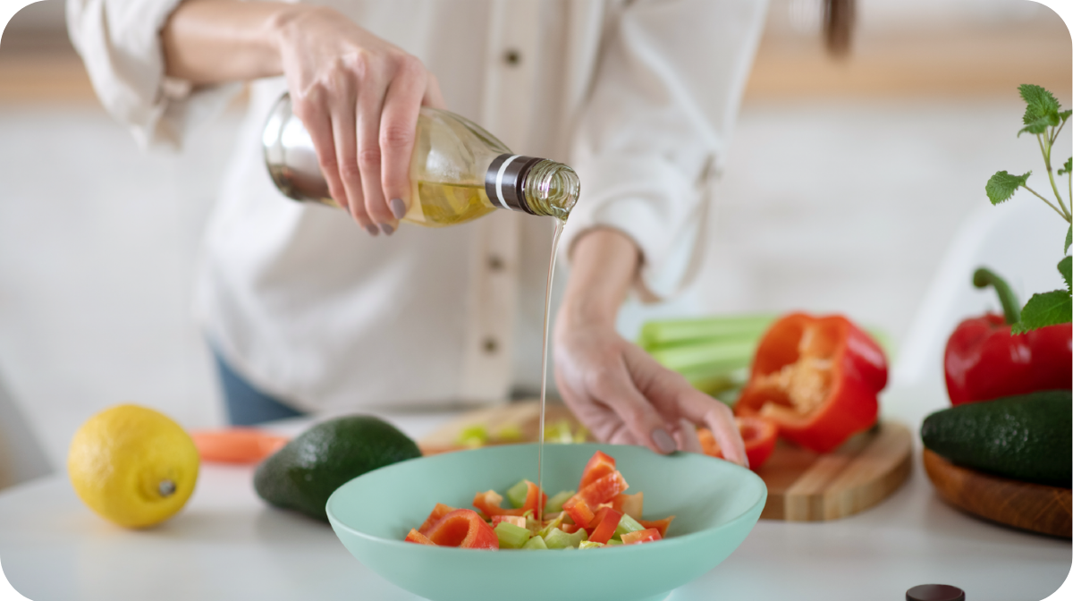 person pouring olive oil on a salad