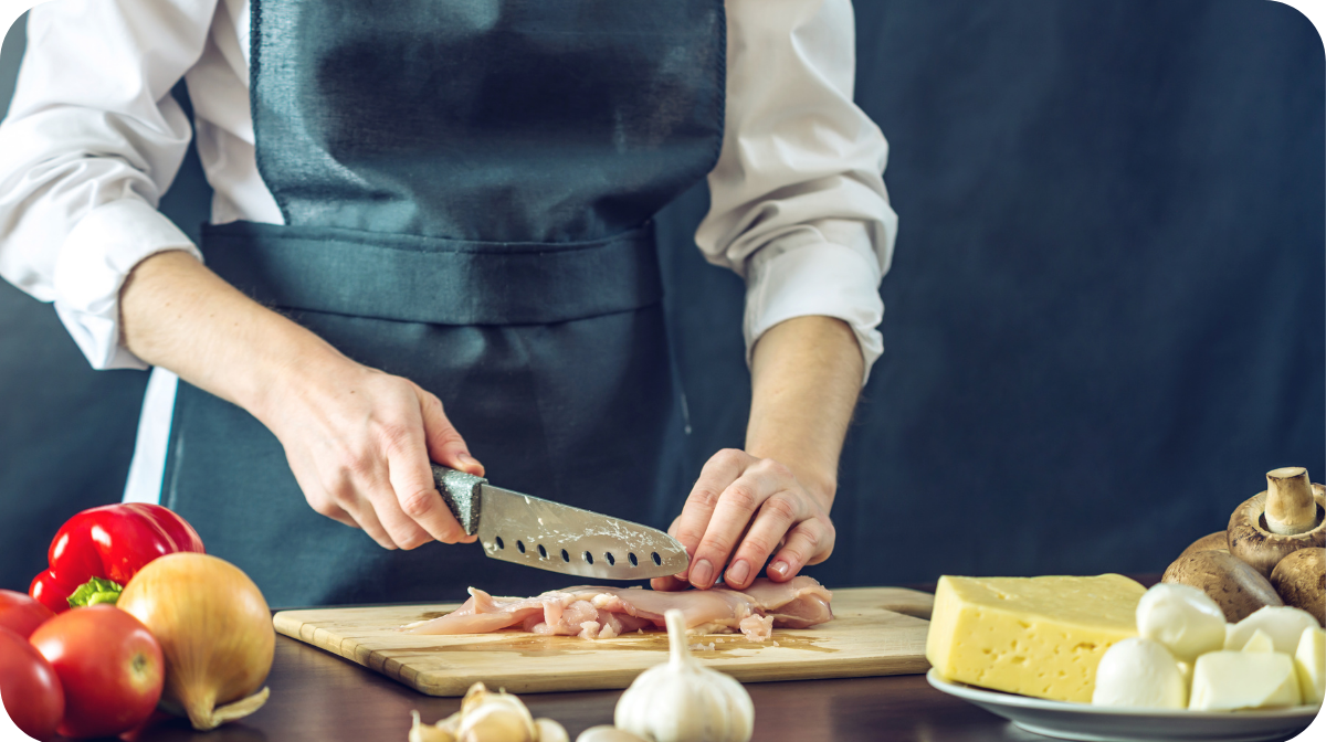 chef in black apron chopping vegetables