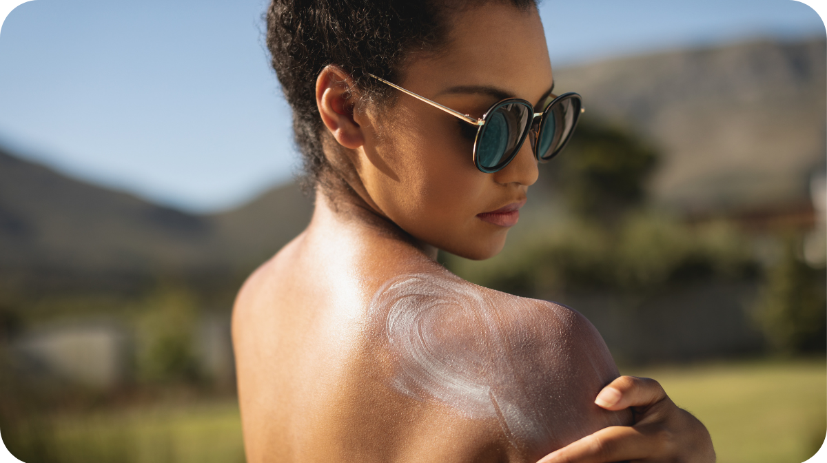  young mixed race woman applying sunscreen on shoulders in backyard of home on a sunny day